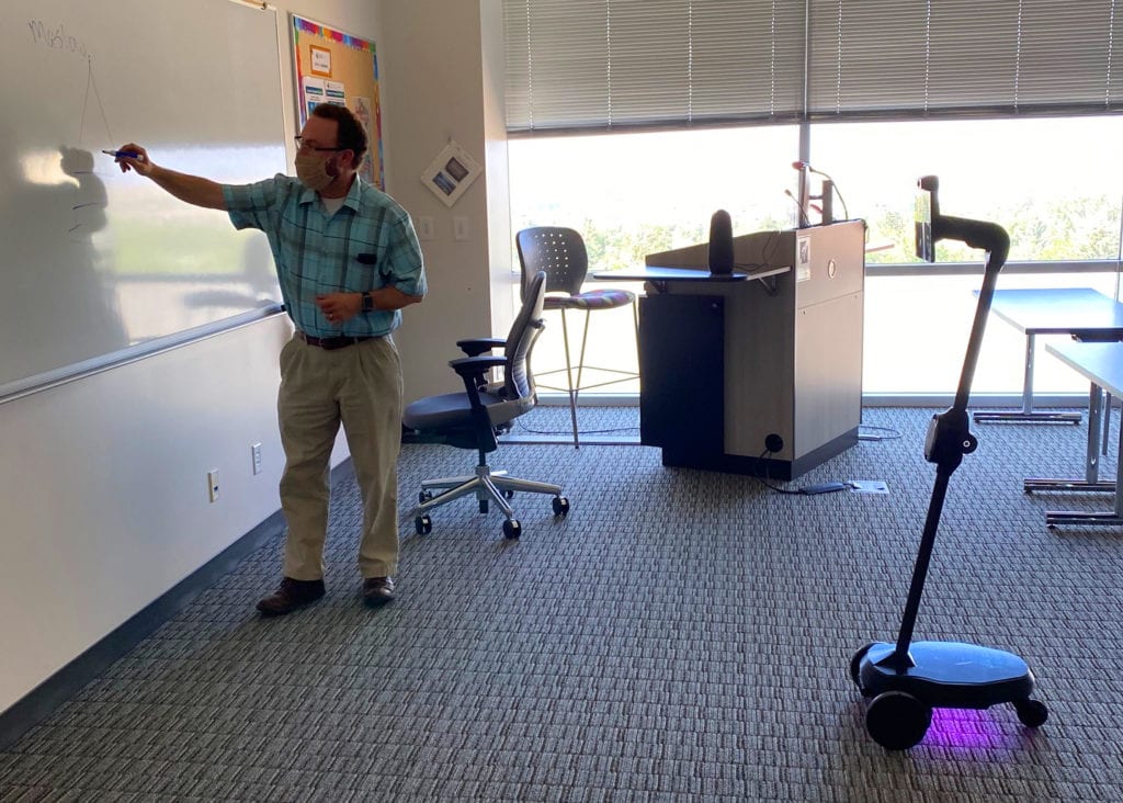 Faculty member R. Paul Maddox uses one of the two Ohmni robots in the classroom